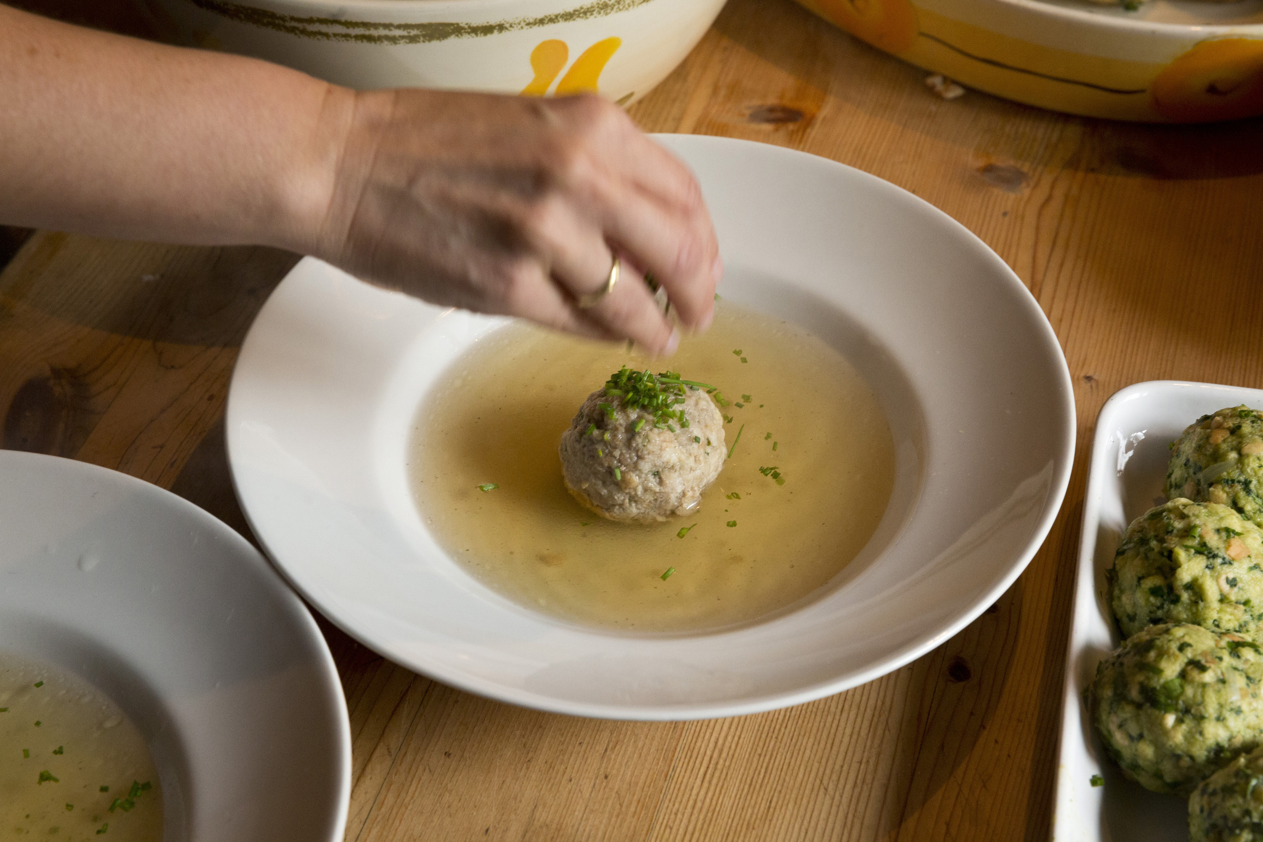 Woman seasoning a soup with dumplings ready to serve