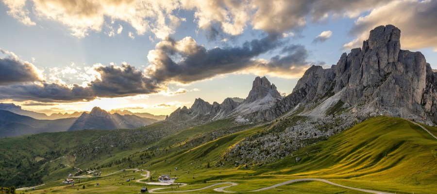 Pass road, green meadows and mountains in the background