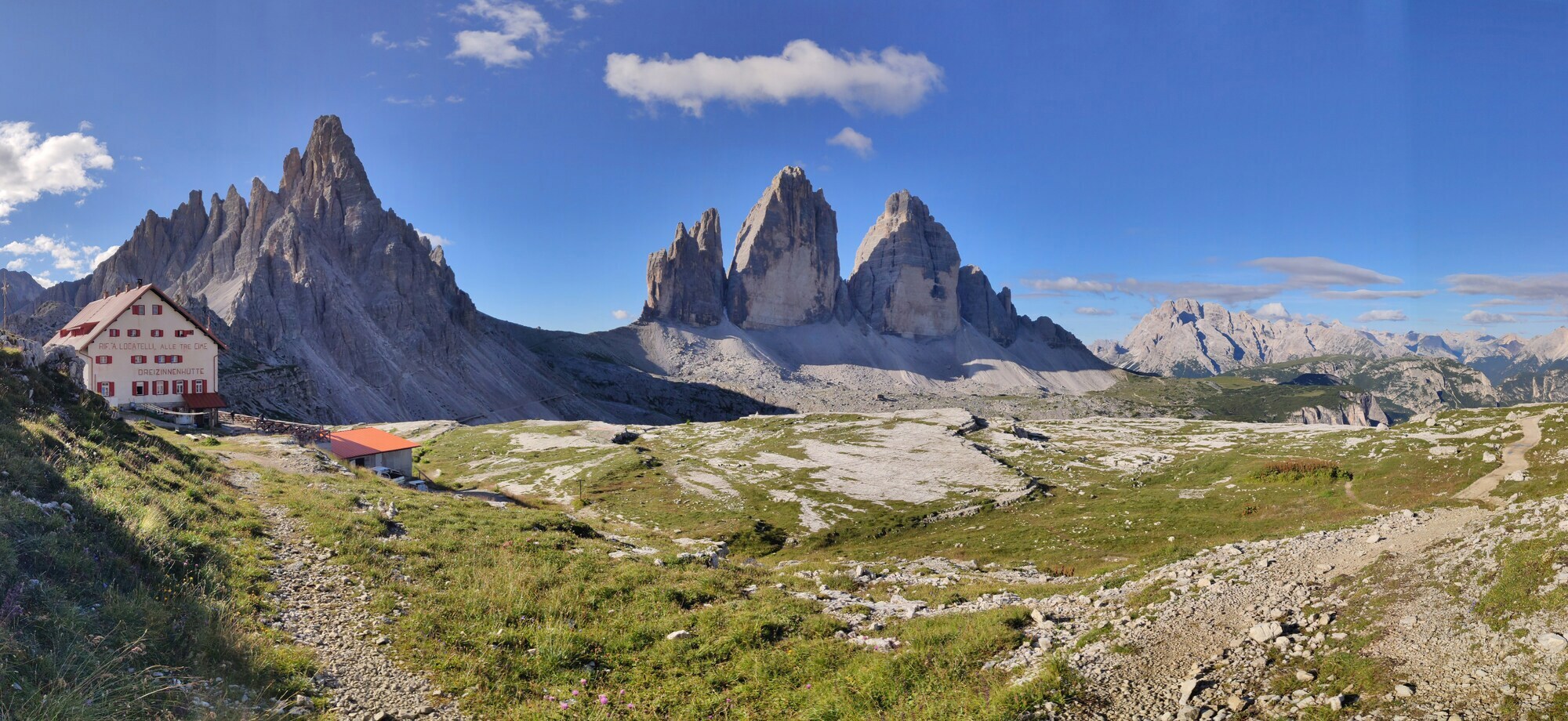 Mountain peaks, alpine meadow and mountain hut with clear blue sky