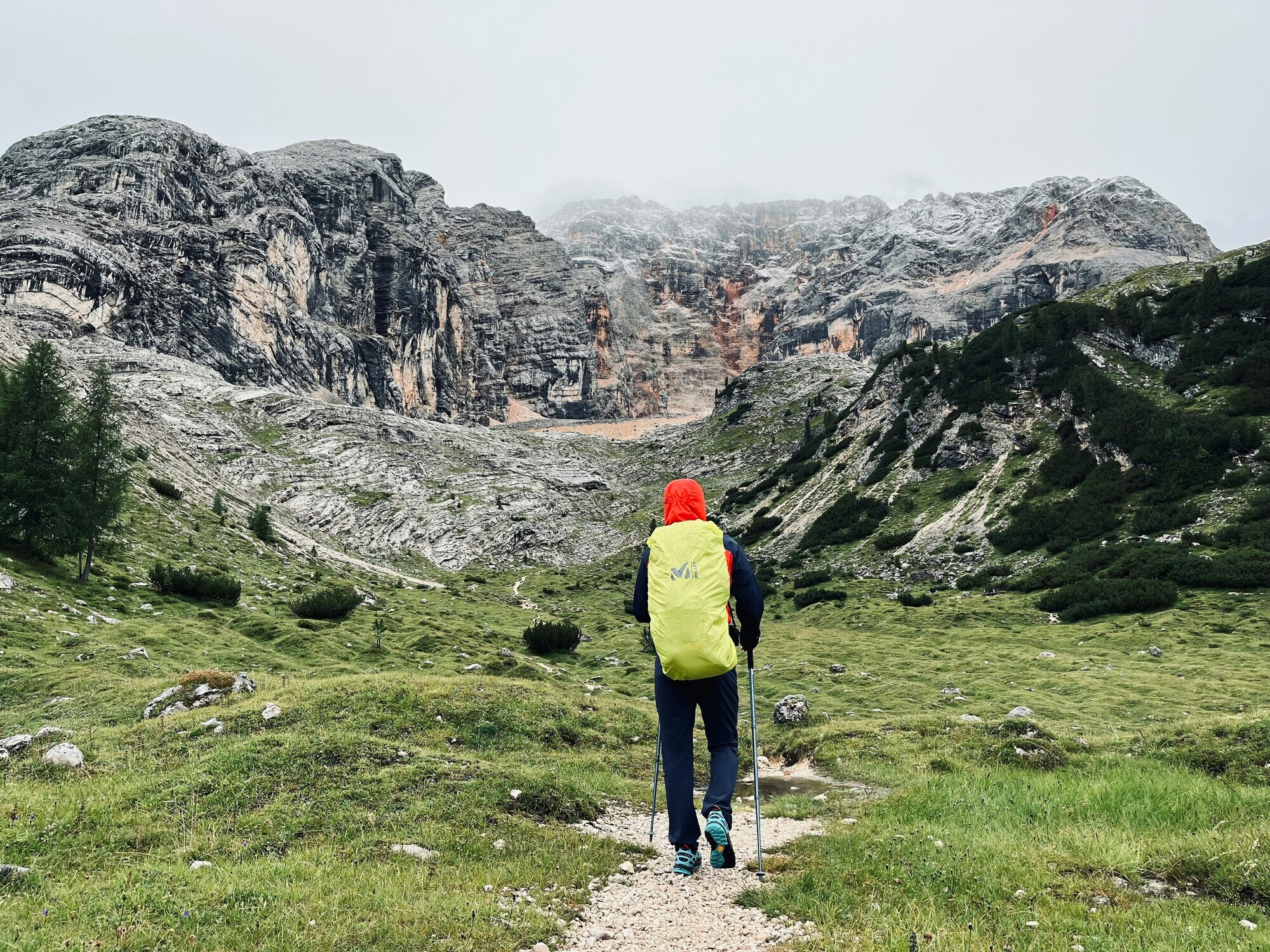 Hiker with snow-covered backpack in the foggy mountains