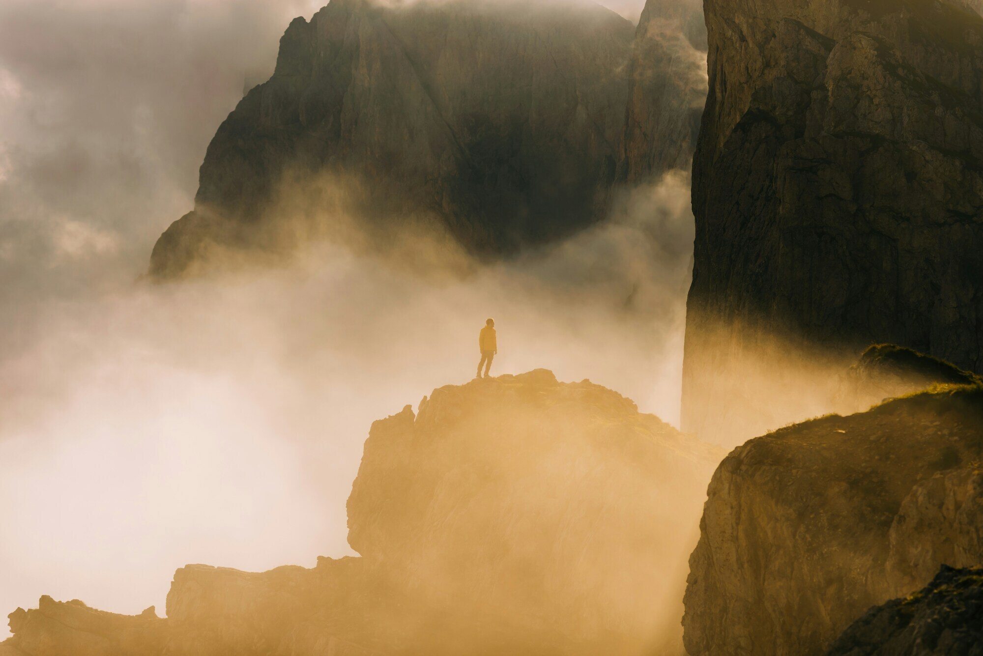 Distant view of a hiker amidst misty rocks in diffuse light