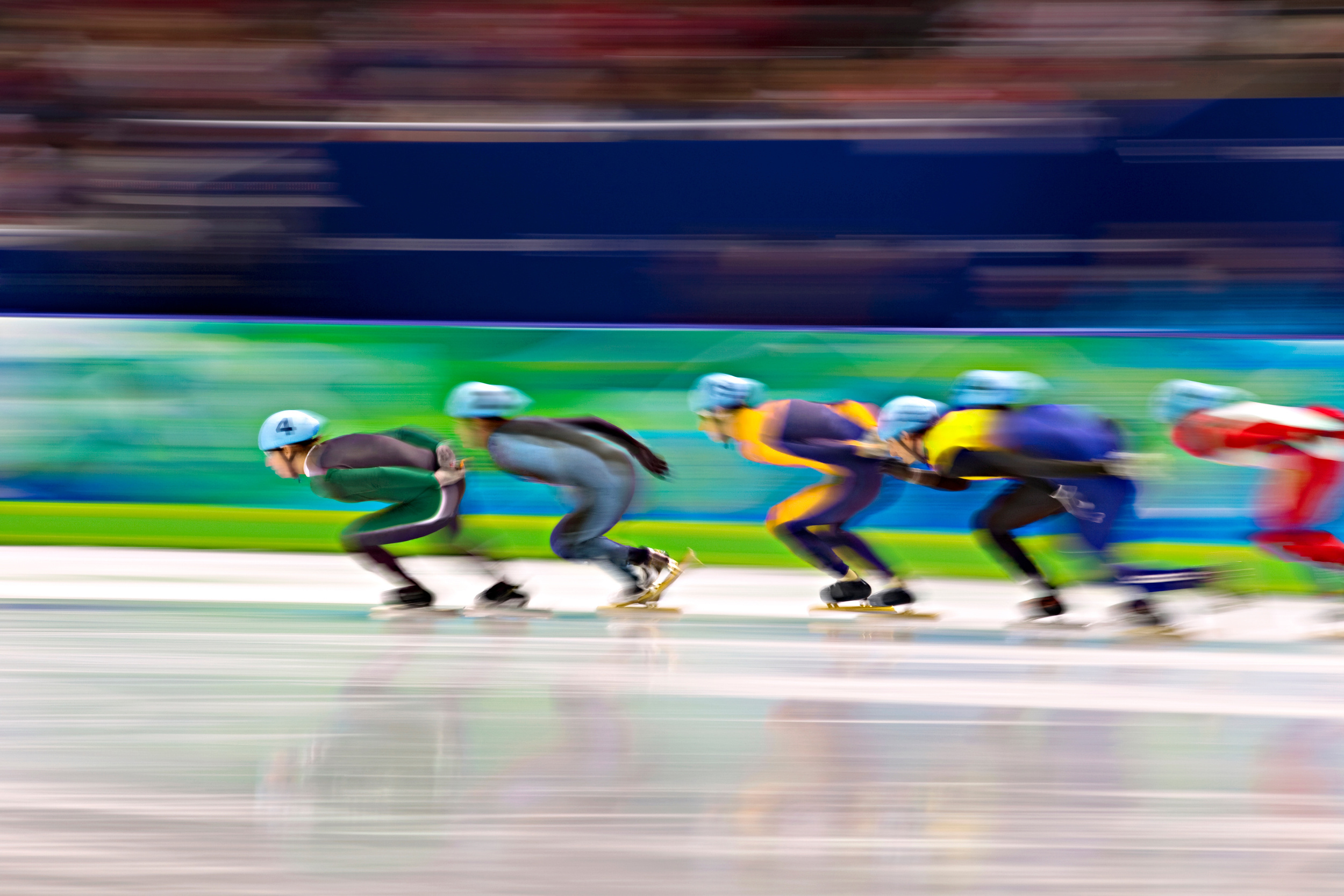 Movement shot of several speed skaters in colourful outfits during the race