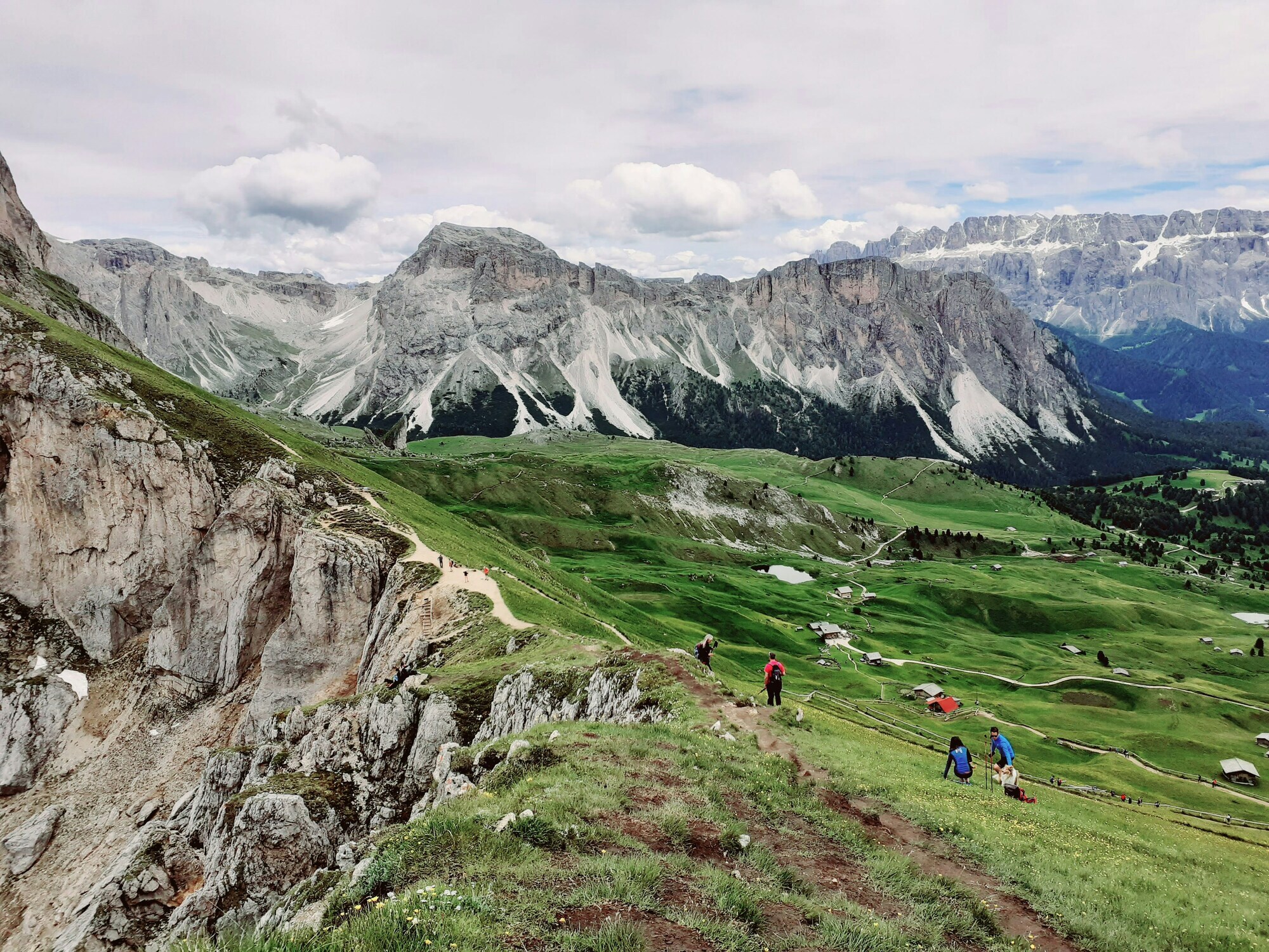 Hikers in a mountain pasture with peaks in the backgrounds