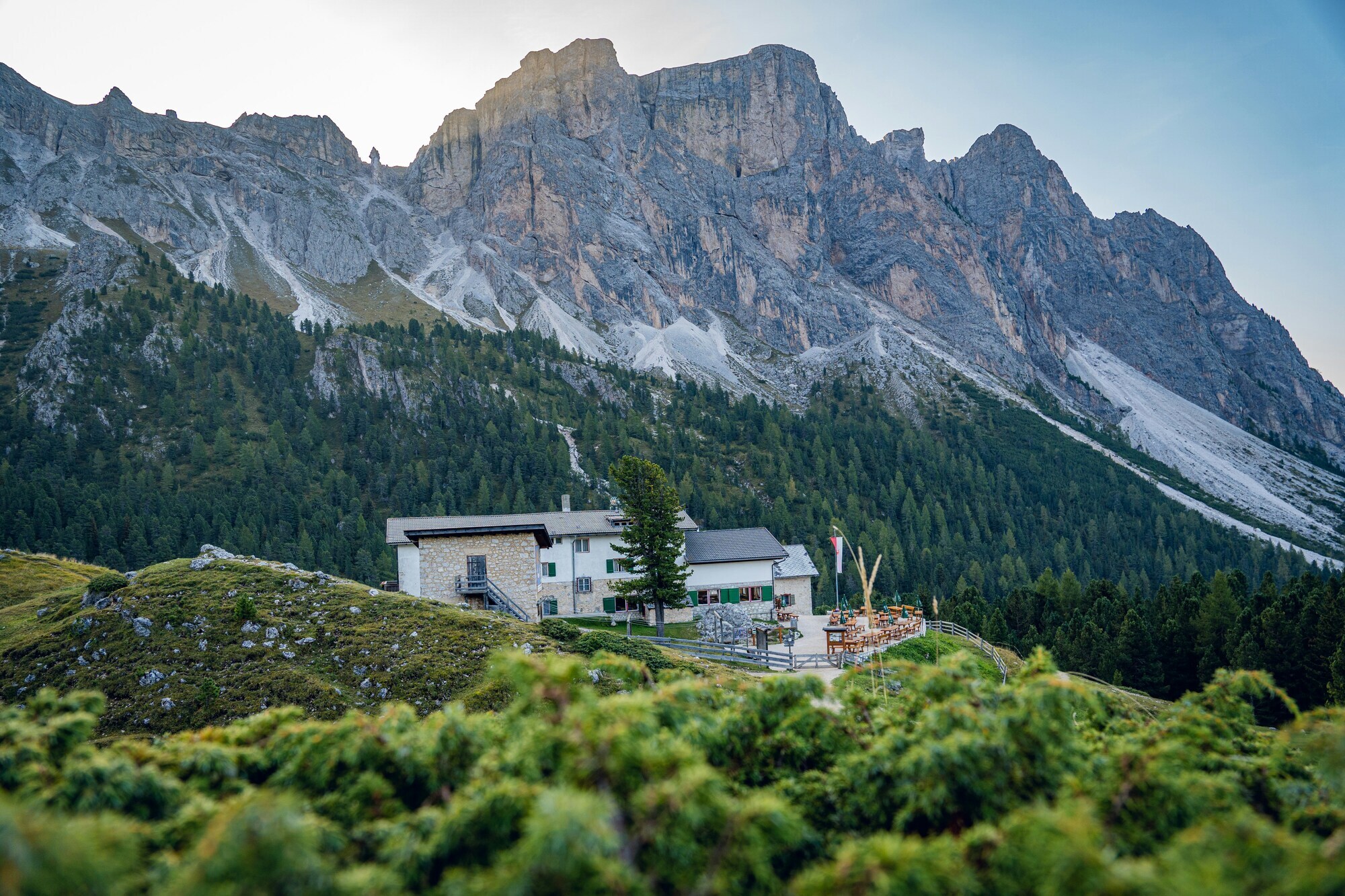 Grey mountain hut in front of pale Dolomites mountains