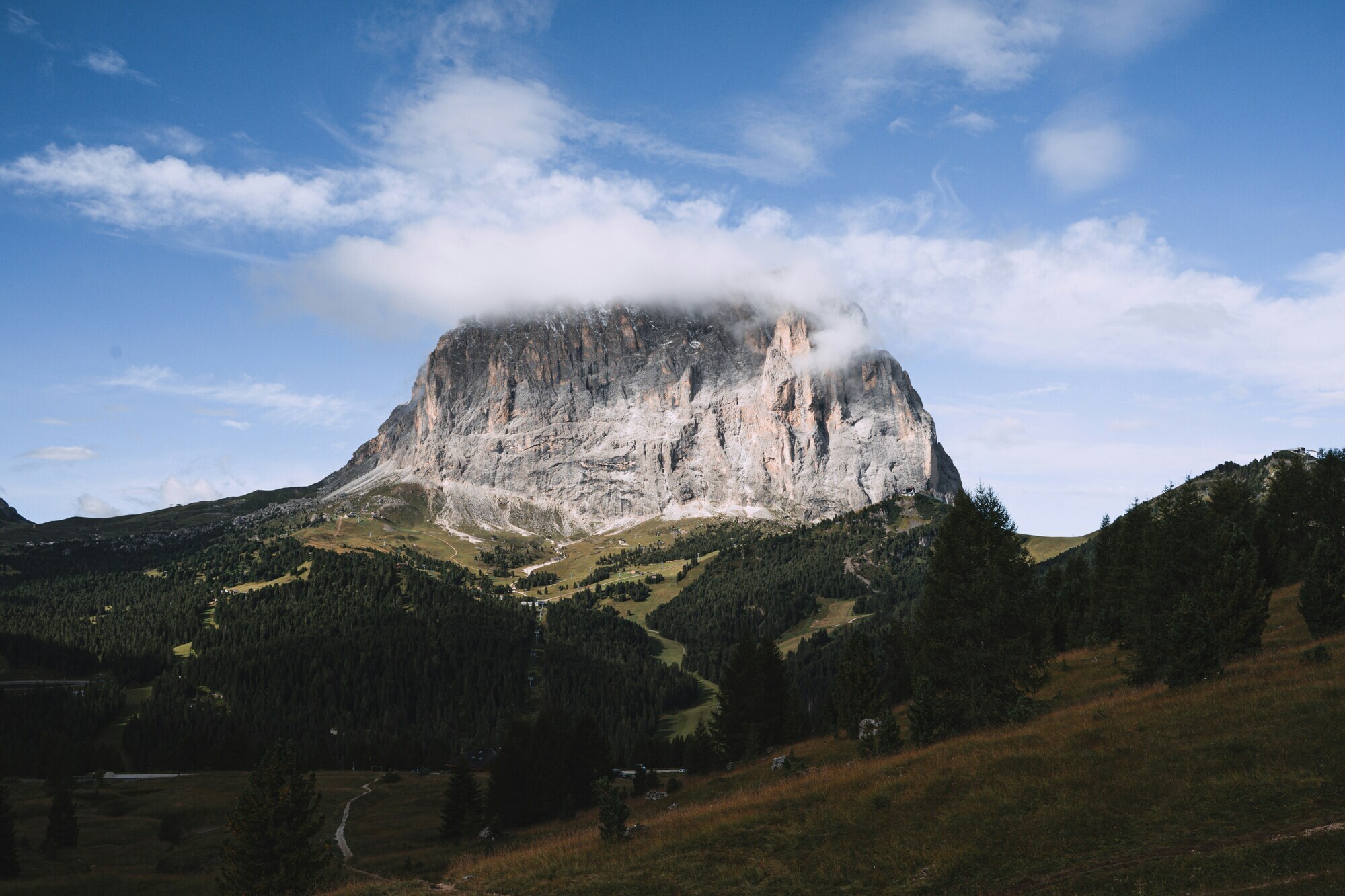 Single-stadning peak covered with fog and green hills