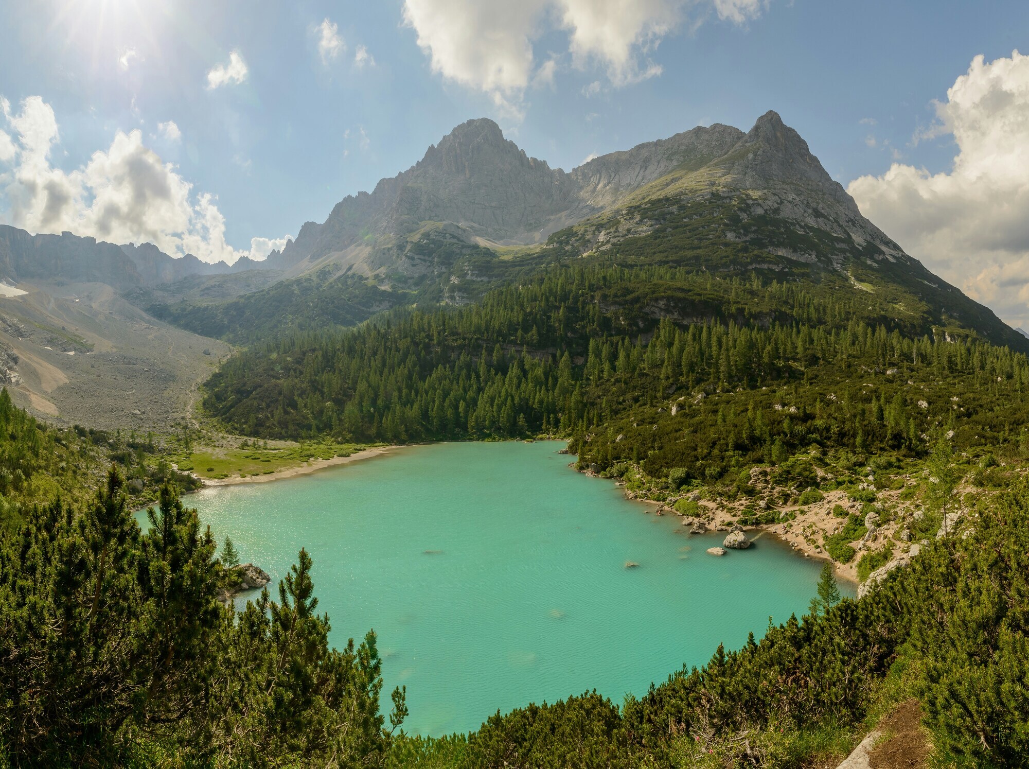 Blue mountain lake in the middle of woods, framed by high peaks