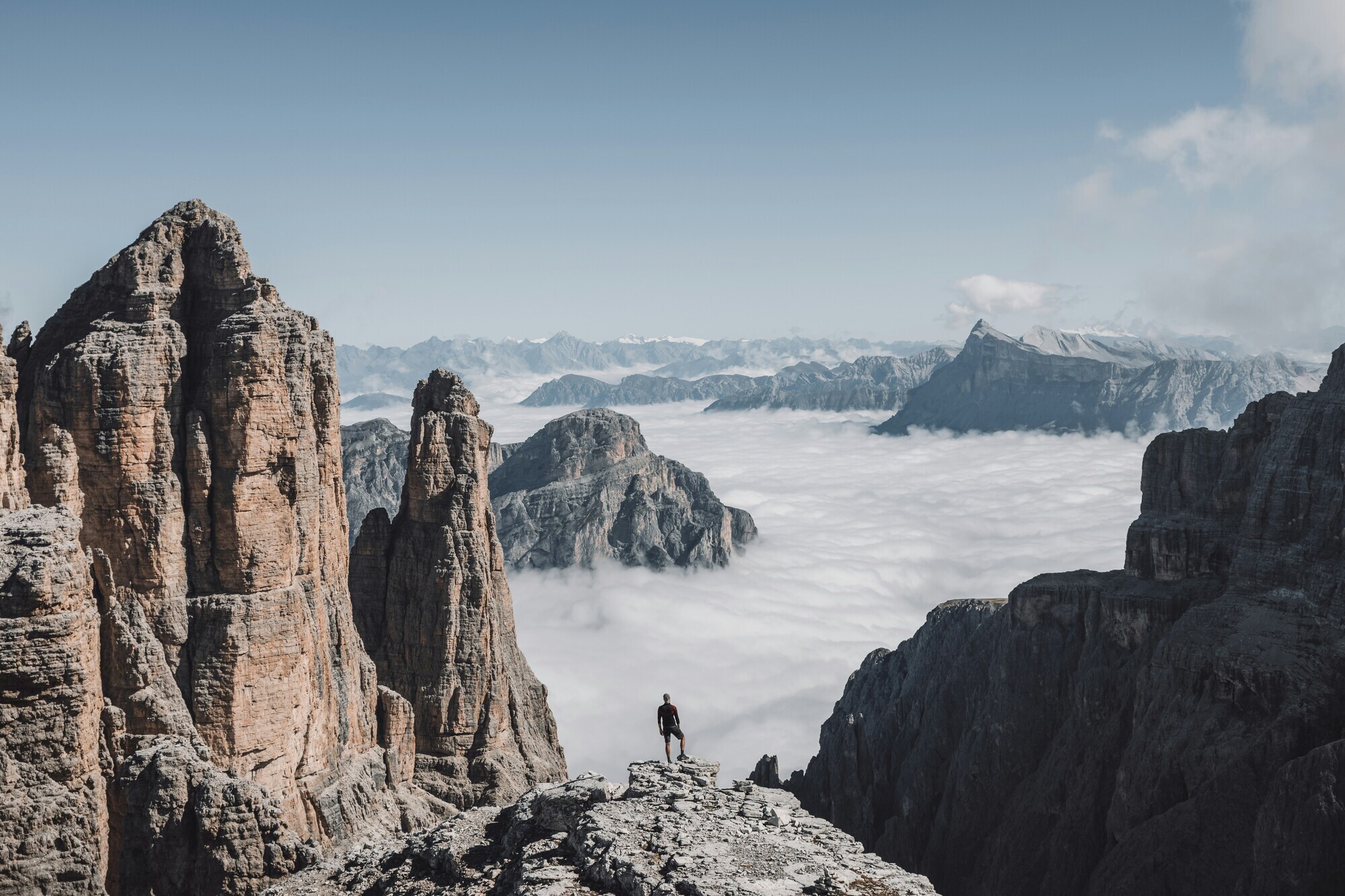 Man standing on a mountain watching a valley covered with clouds