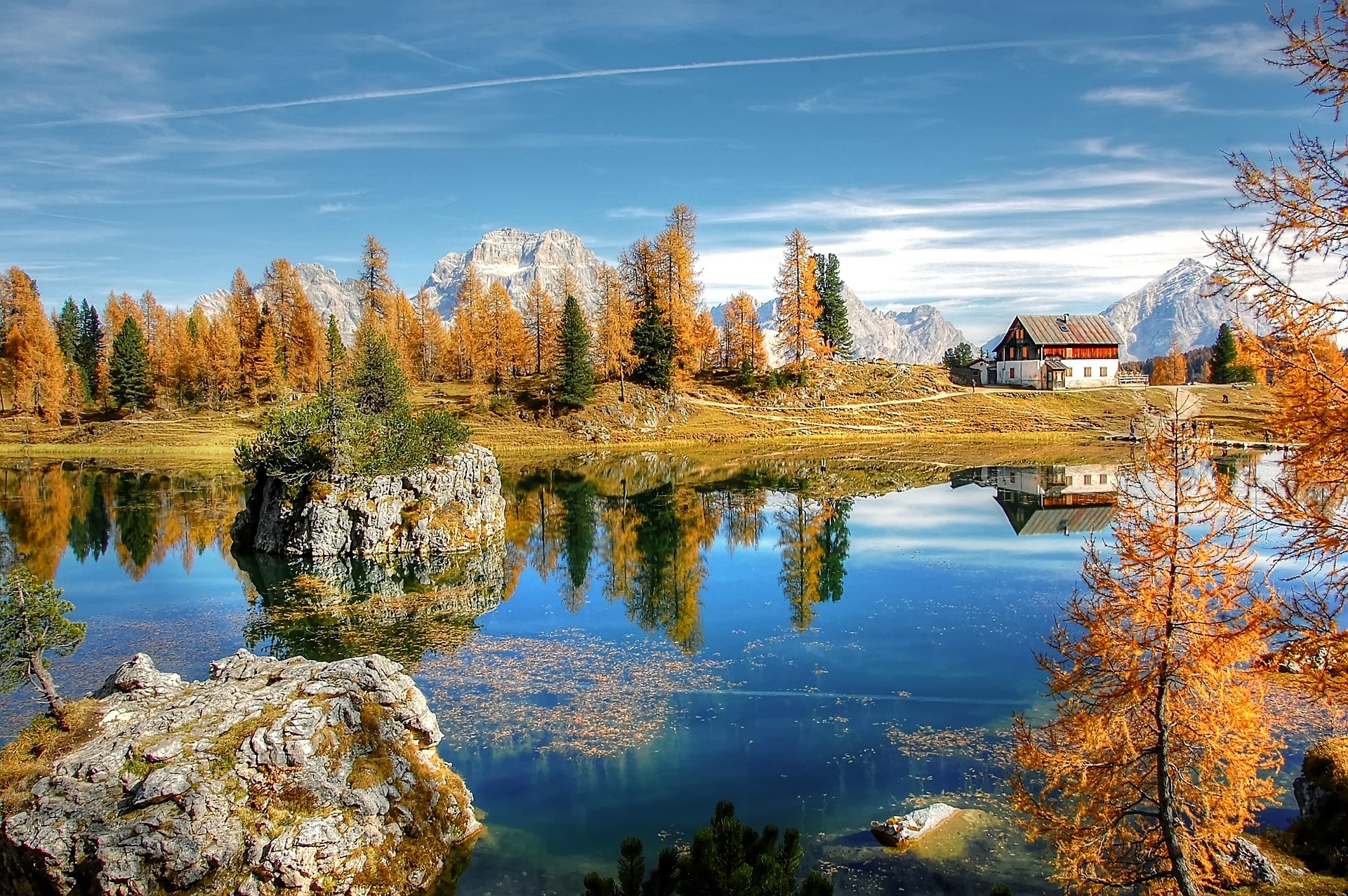 Mountain hut and golden autumn trees reflected in a lake