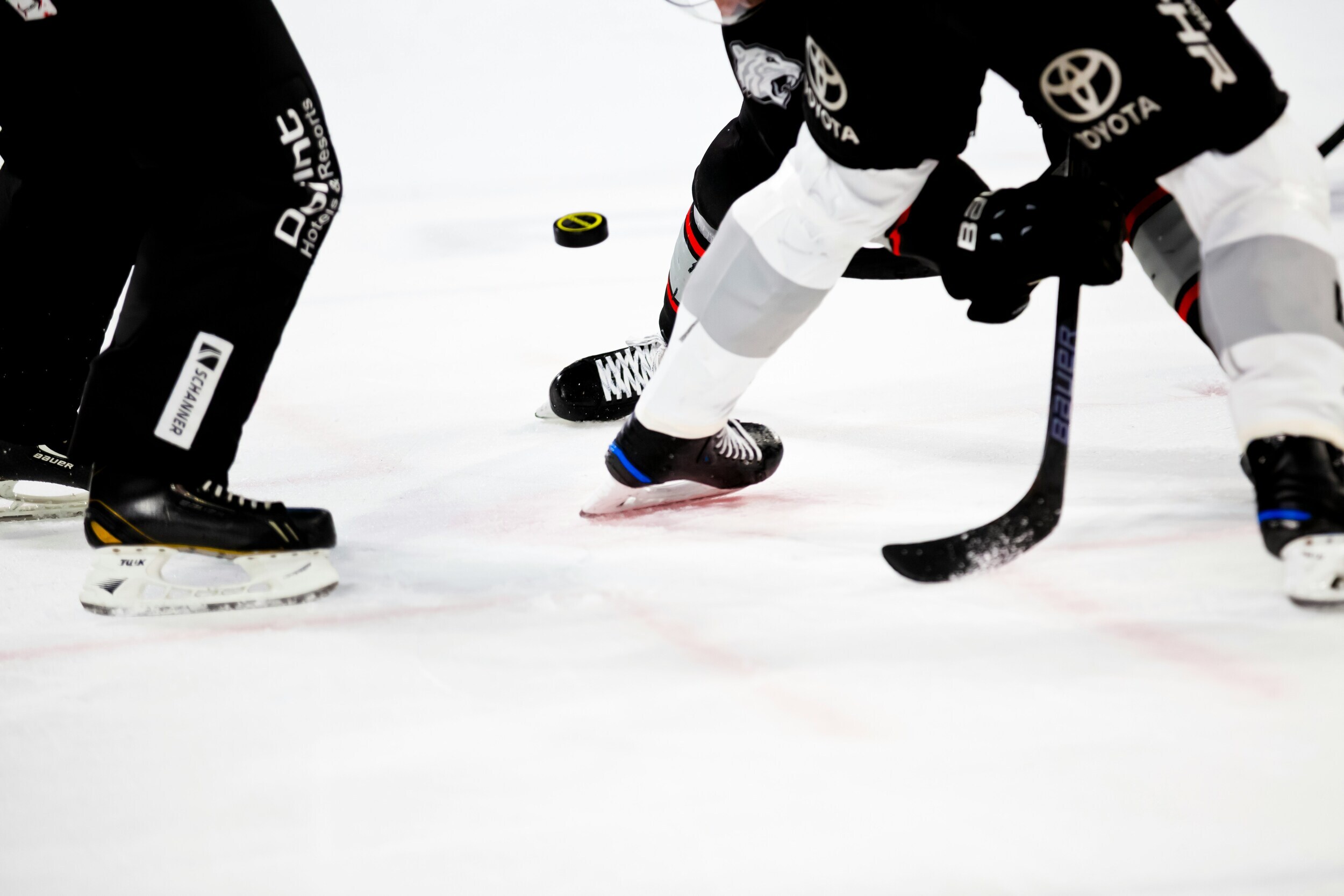 Ice hockey player on the ice, only legs, sticks and puck are visible